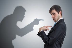 Shadow of man is pointing and blaming businessman. Conscience concept.